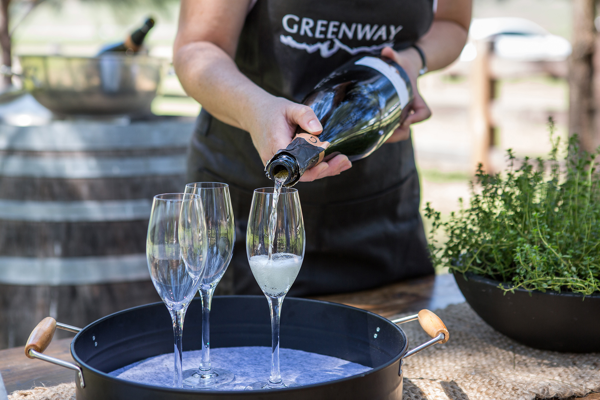 Man pouring wine in 3 glasses outside 